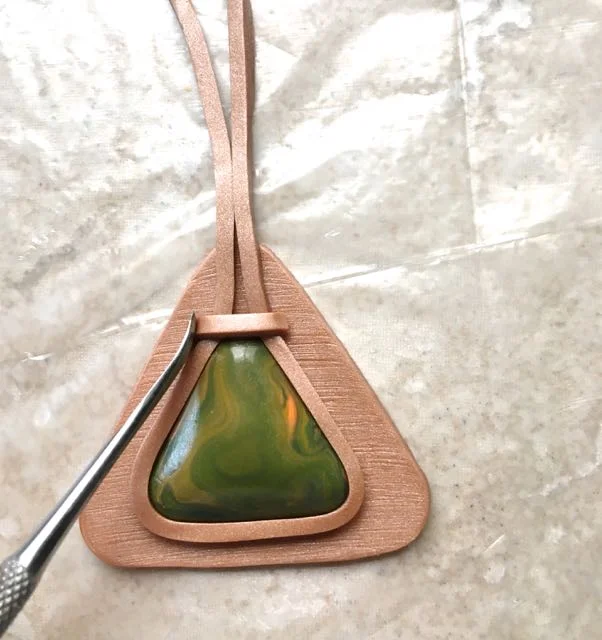 step 17 - Position the pieces horizontally above the gem. Use a sculpting tool to smooth the edges at the sides. Do not press down on the center of the pieces so they will maintain their uniform shape.
