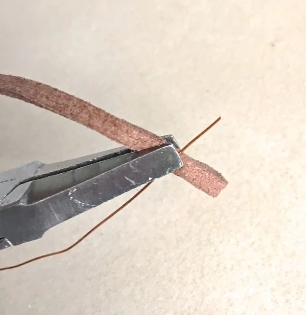 step 10 - Finish the raw cord ends by folding them over .50” to form a loop. Hold the fold together with needle nose pliers. Insert a small length of 26 gauge wire under the pliers so that the end is held securely with the cord.