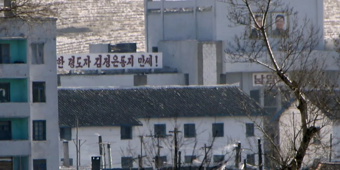A propaganda slogan and portraits of former North Korean leader Kim Jong Il (R) and his father and founder of North Korea Kim Il Sung (L) are seen in a North Korean village on the banks of the Tumen river, which is seen from the Chinese side in Tumen, China, January 7, 2016. REUTERS/Kim Kyung-Hoon