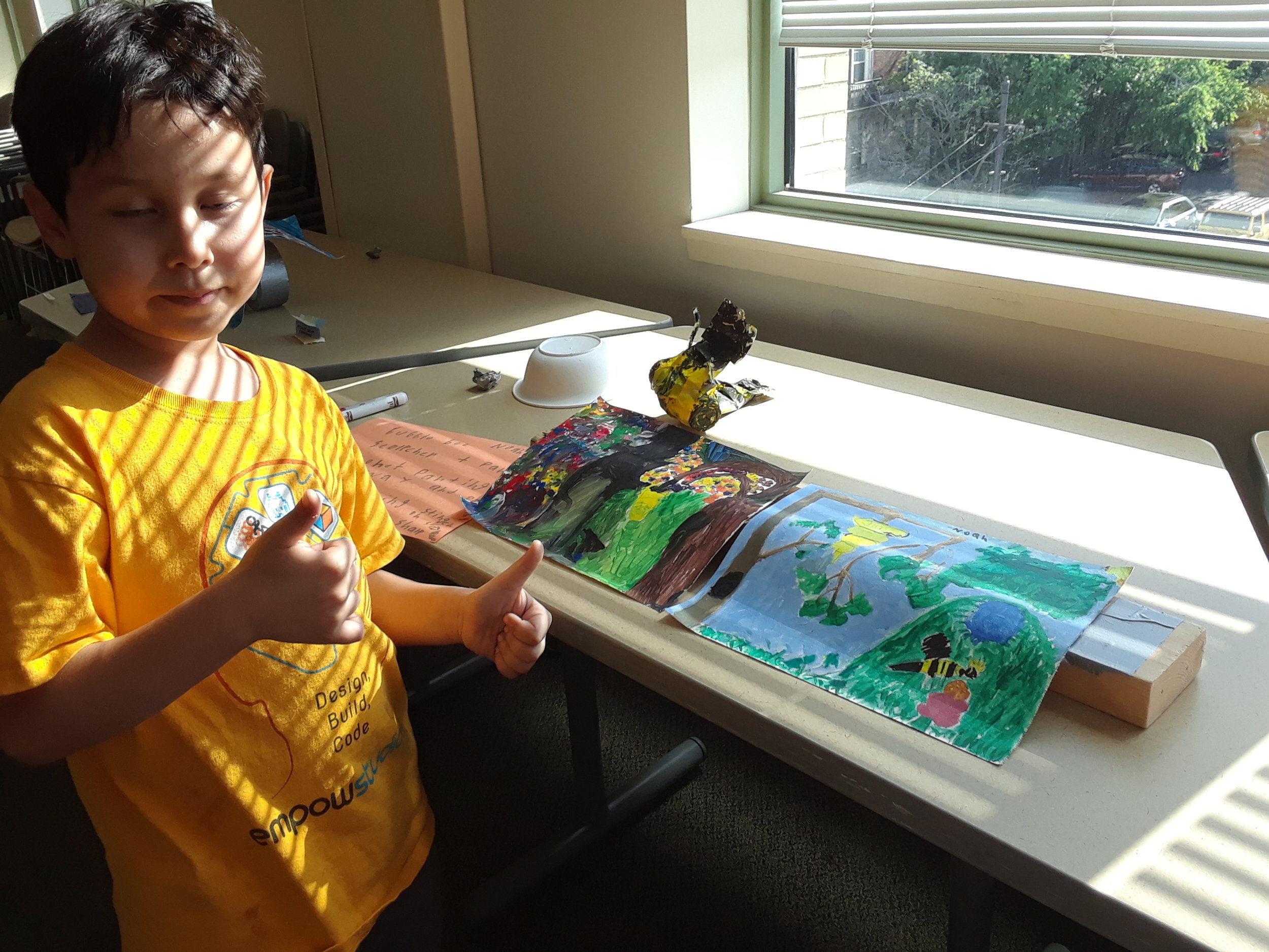 Student with his two paintings and sculpture inspired by bees.