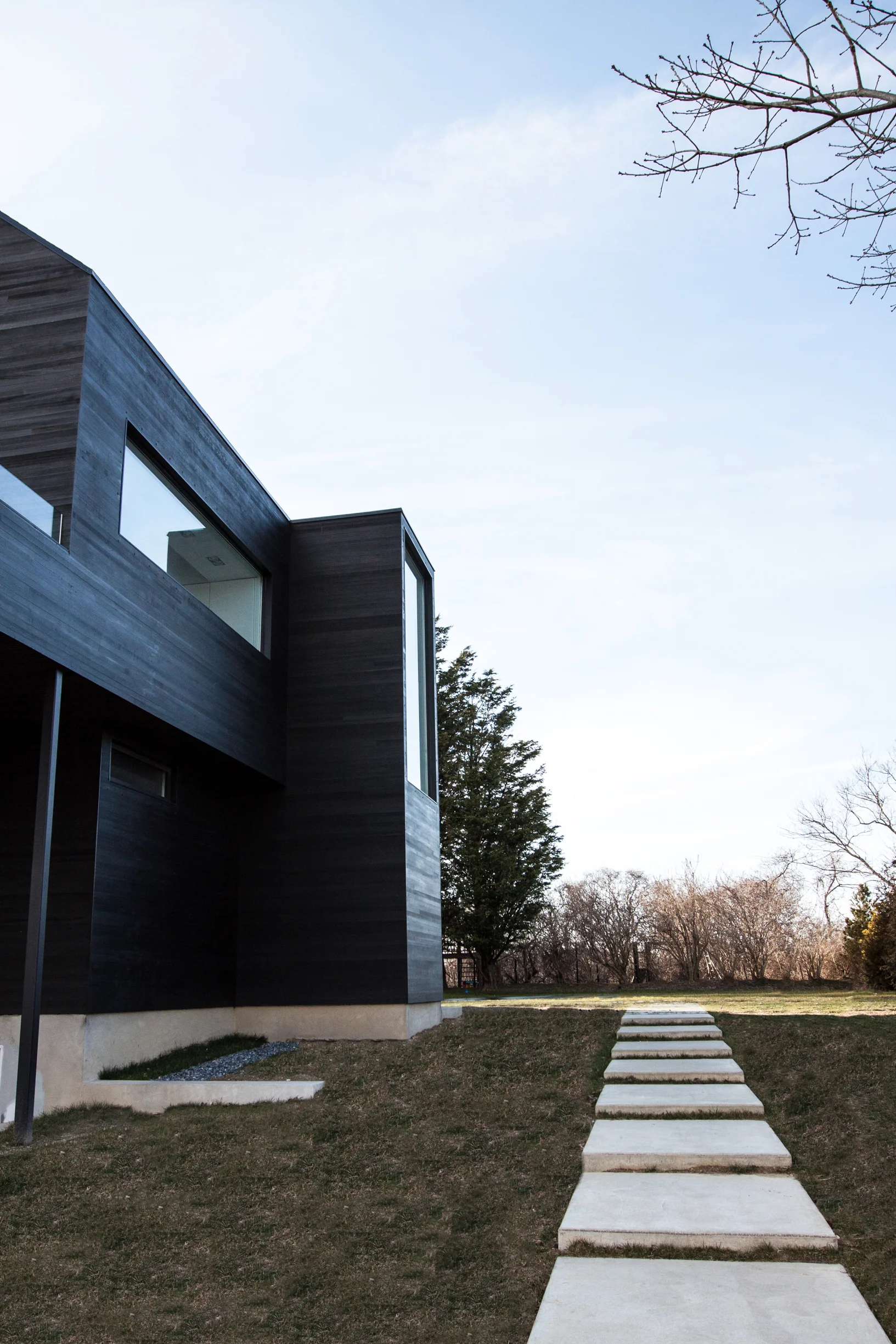 Black Modern barn house with Shou Sugi Ban cedar siding, windows, and landscaping