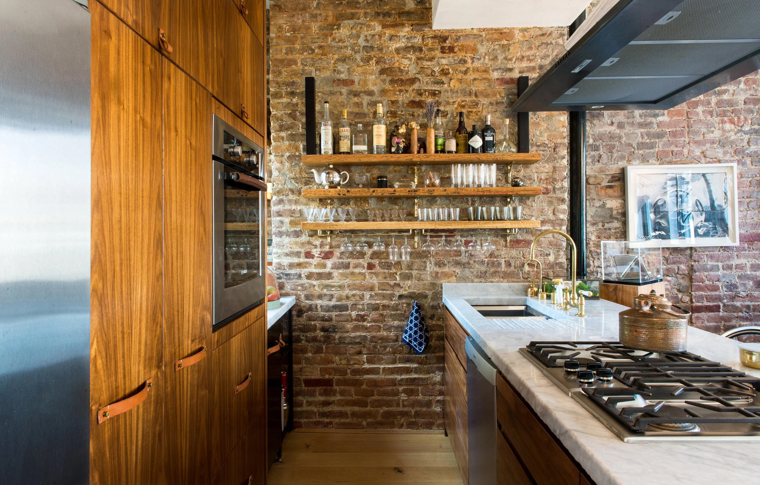 Modern New York apartment kitchen with open shelving, exposed brick, marble slabs and American walnut cabinetry