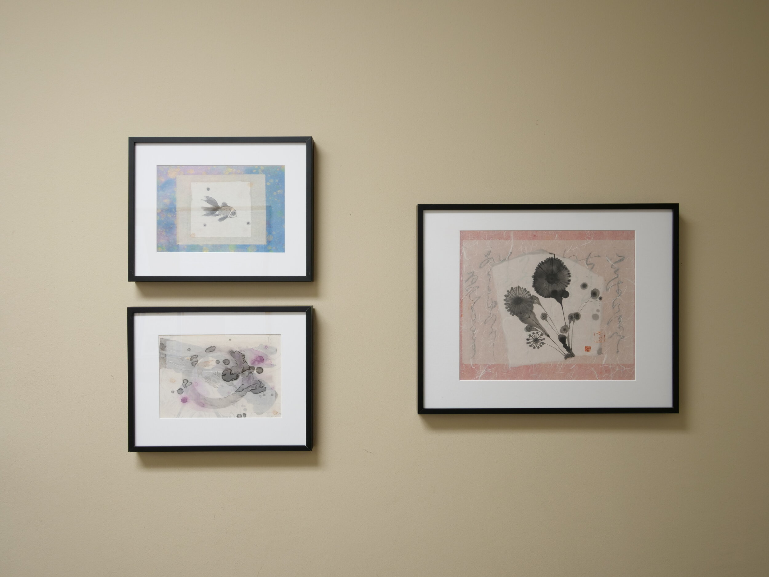 Three abstract pieces in black ink and soft colors, all displayed in black frames with white matting.