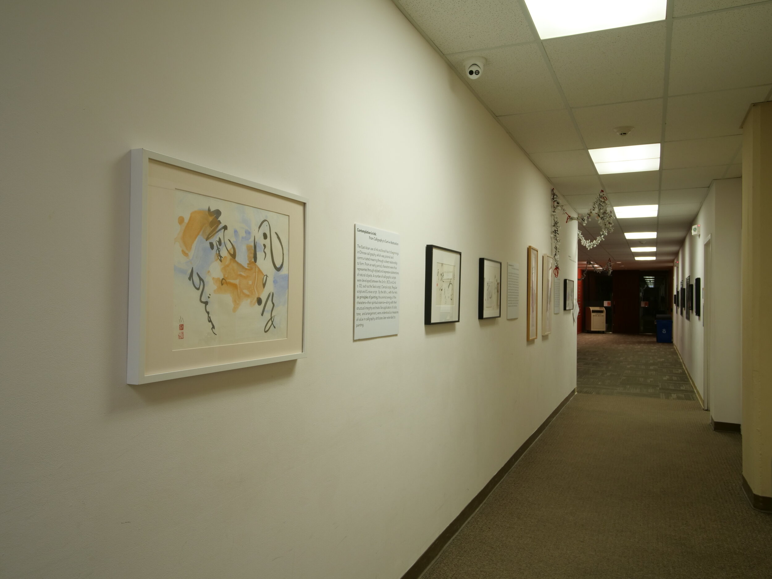 View along a wall featuring multiple framed ink drawings.