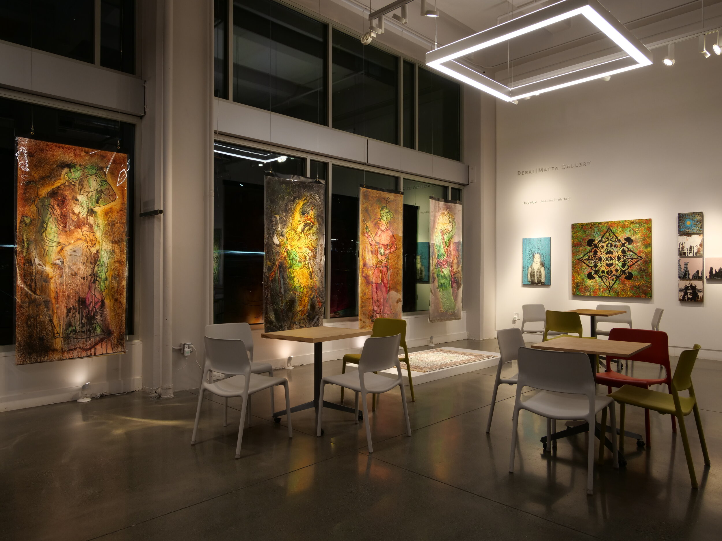 Gallery view of four large panels featuring figures in warm tones hung along the windows.  (Copy)