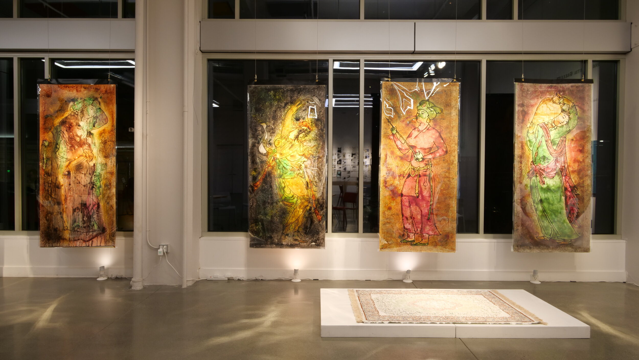 Four large panels of life-size human figures hang in the front windows.  A platform with a rug atop it sits in the foreground.