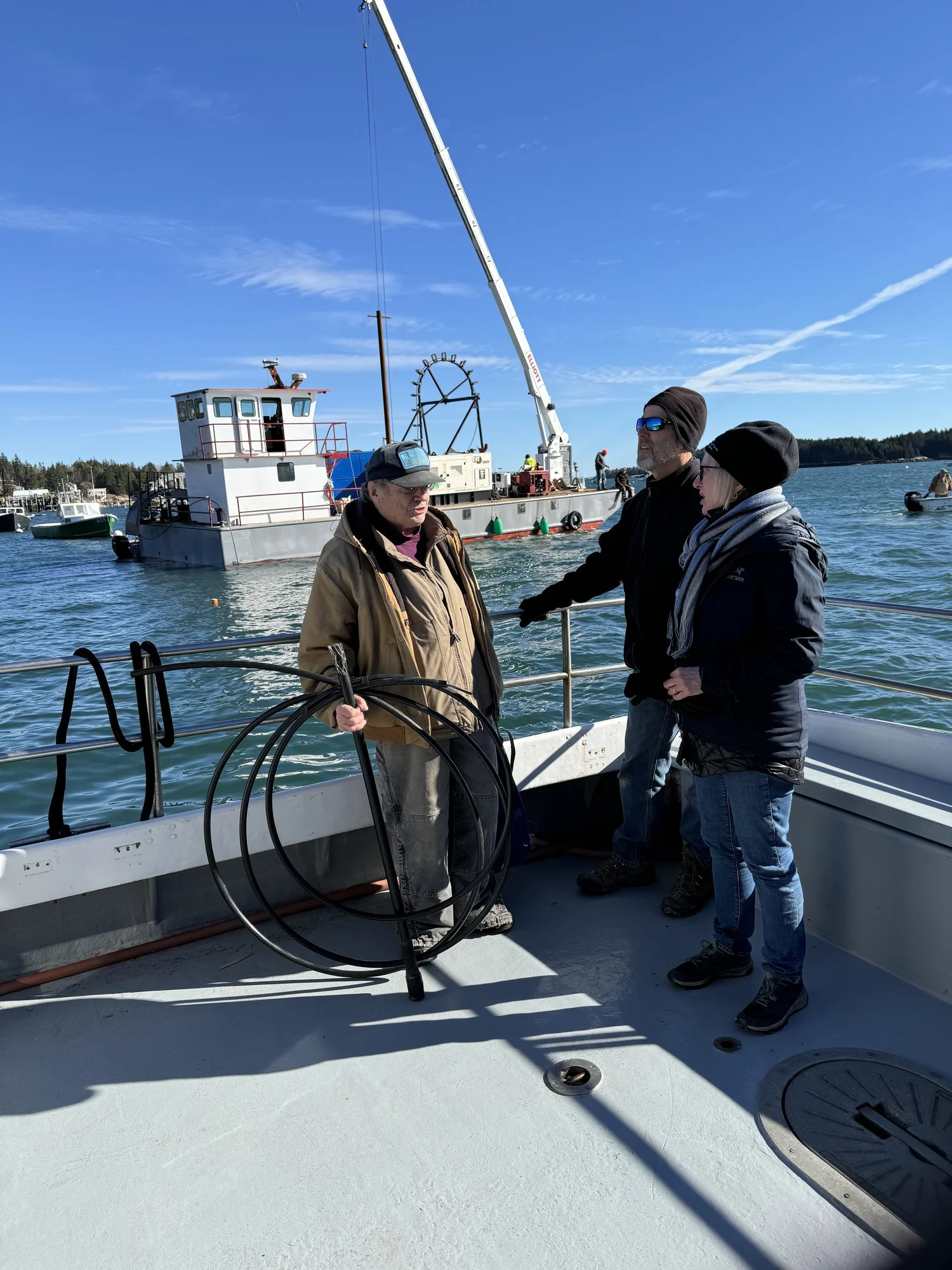 Crew on a boat deck beside a crane barge, laying Isle au Haut's subsea fiber cable