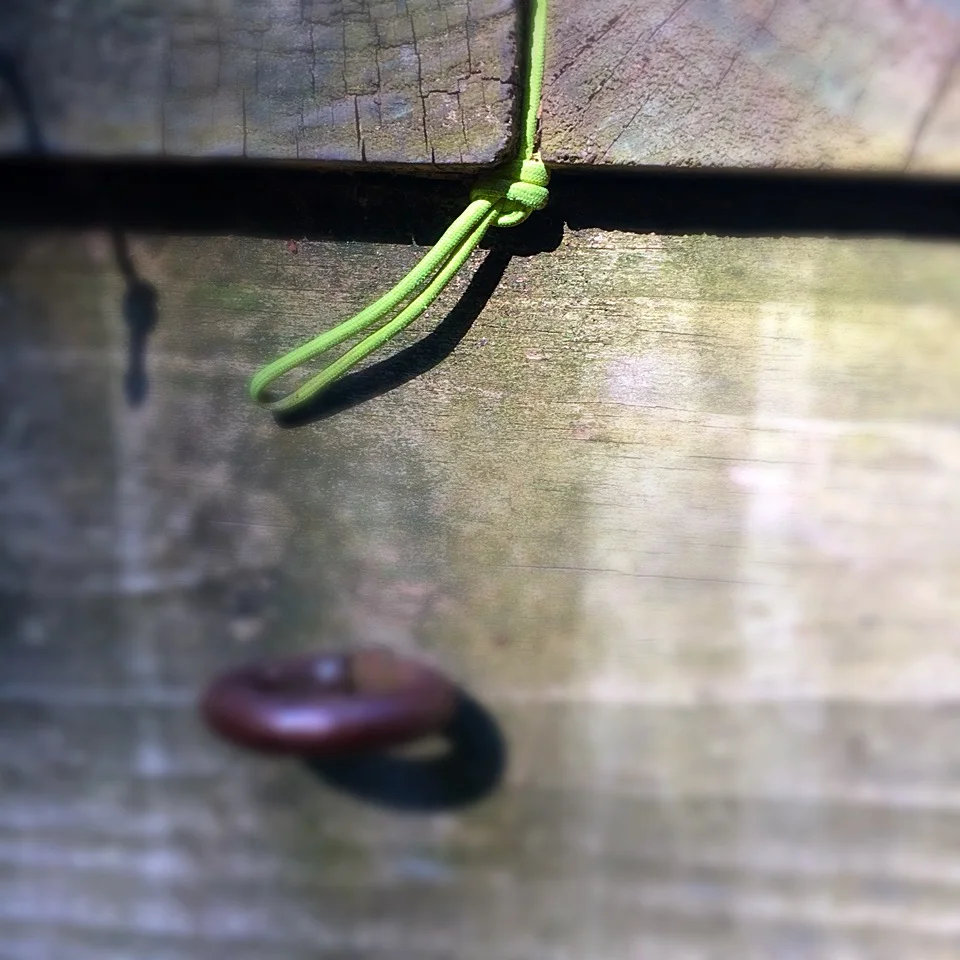 Slide the side guy line knot between the boards.