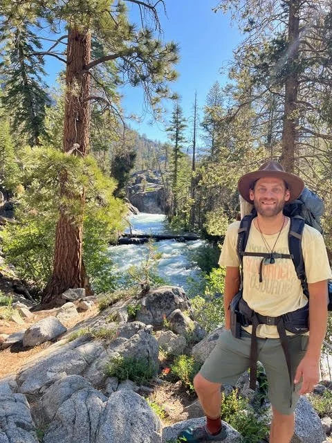 Jonathan Stauf Outside Now Interim Director and Program Mentor in the forest with a river flowing in the background