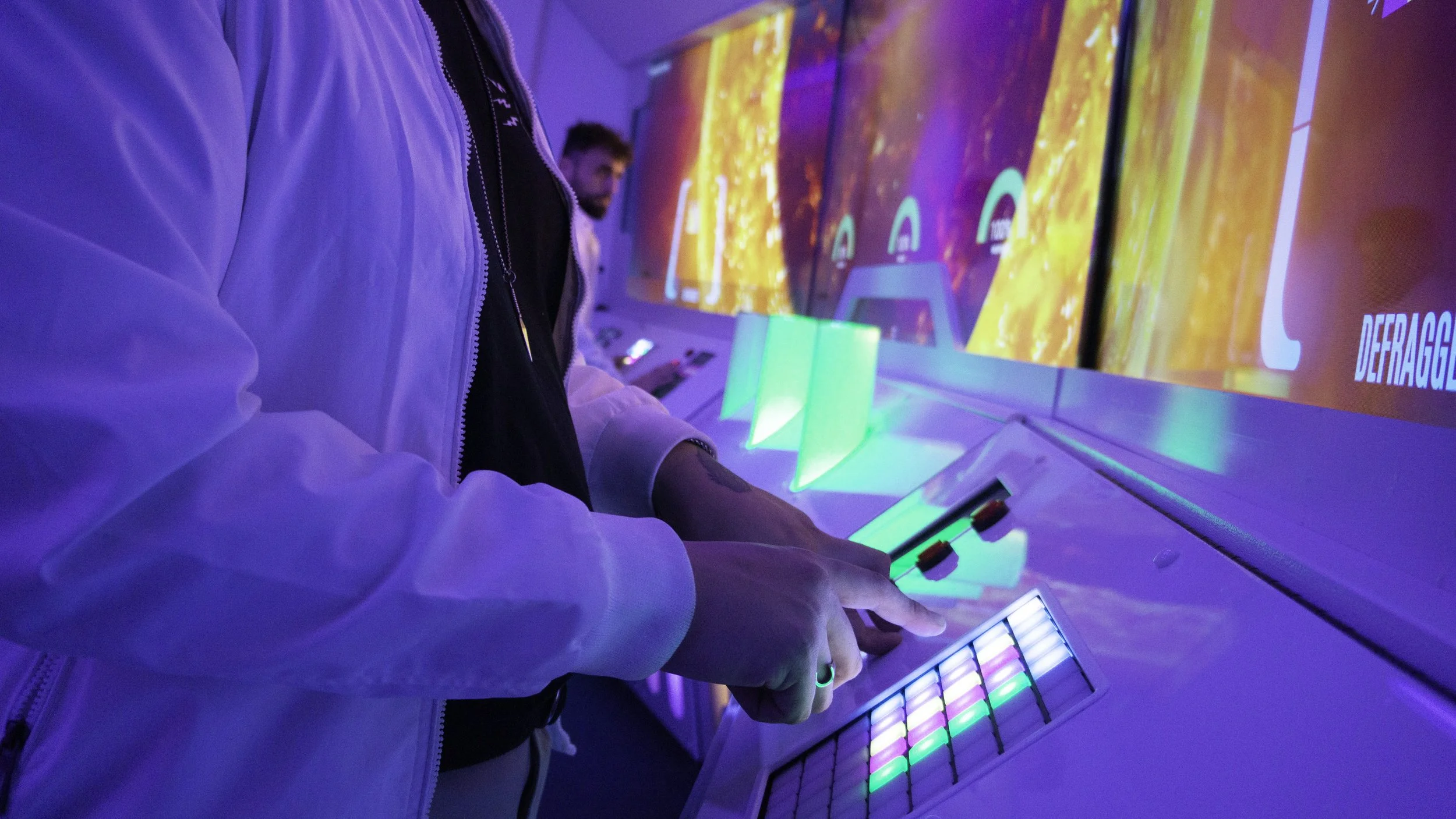 People playing with backlit electronic music equipment at a nightclub or event.