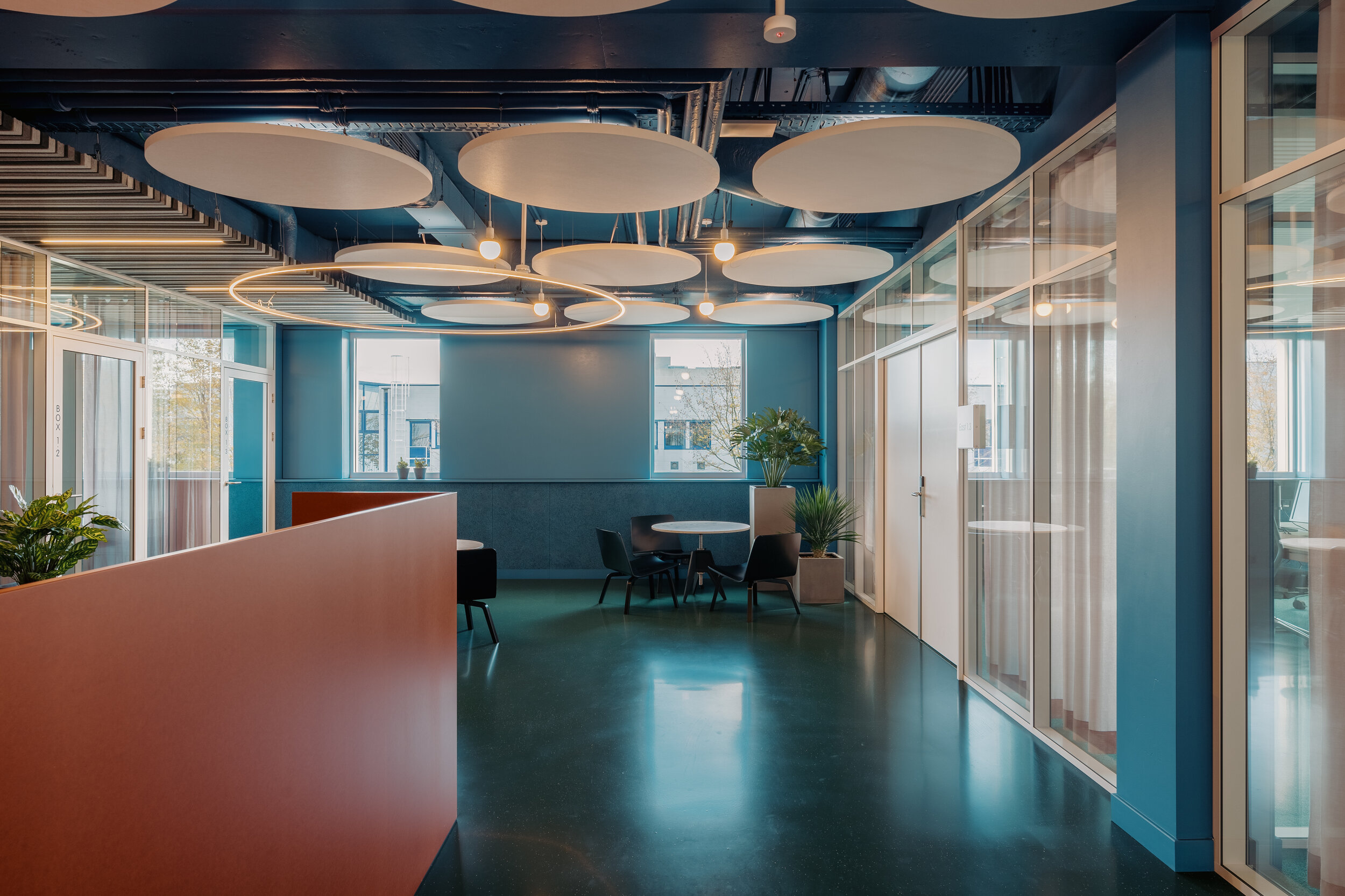  When entering the building through the central courtyard, a colourful whole emerges. Conceived as a contemporary twist on modernism, the vibrant interior takes visual cues from the corporate identity of its main resident with orange accents popping 