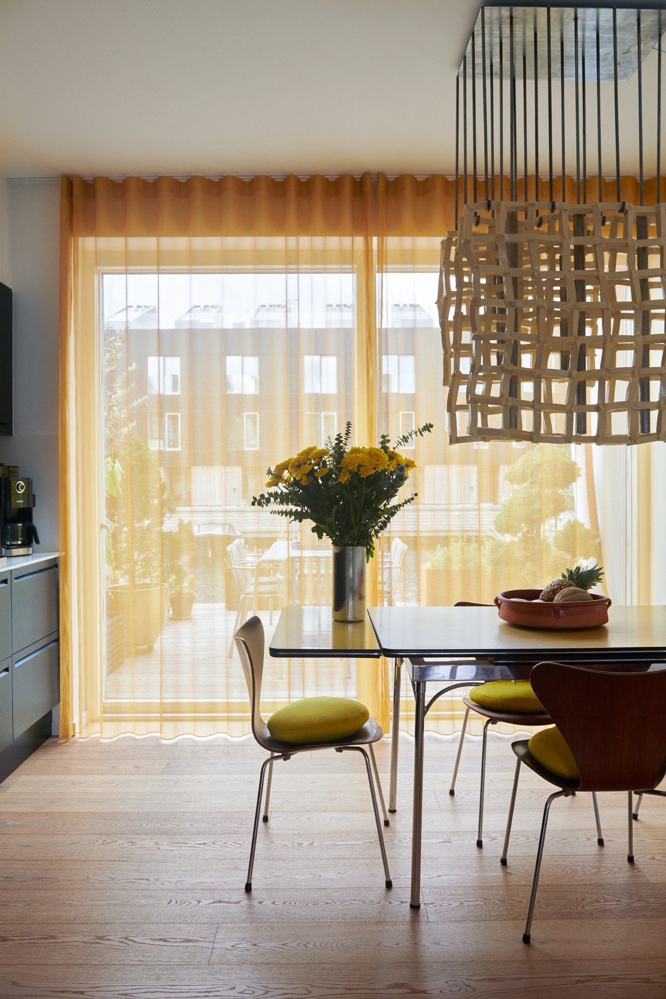  The dining room features a mid-20th-century table surrounded by Arne Jacobsen rosewood-veneered ‘Series 7’ chairs for Fritz Hansen underneath Denys’s ‘Foam Catcher 2.0’ ceiling light. Behind the curtains is the back terrace, overlooking the sea as w