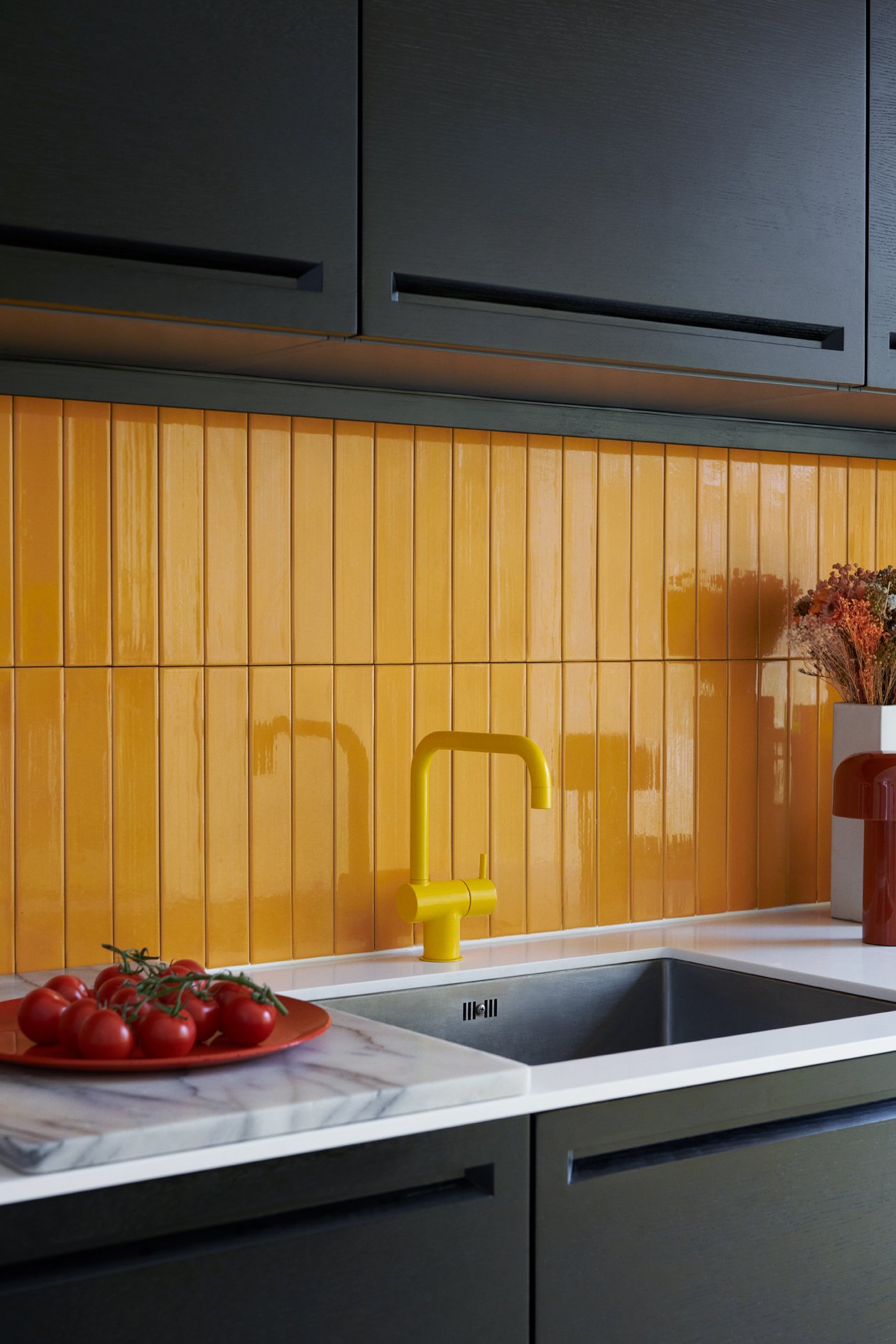  Denys selected glazed wall tiles from Danish brand File Under Pop, and a yellow ‘KV1’ kitchen mixer tap by Arne Jacobsen for Vola, to offset the black-and-white open kitchen specified by the building’s architects. The portable table lamp is ‘Bellhop