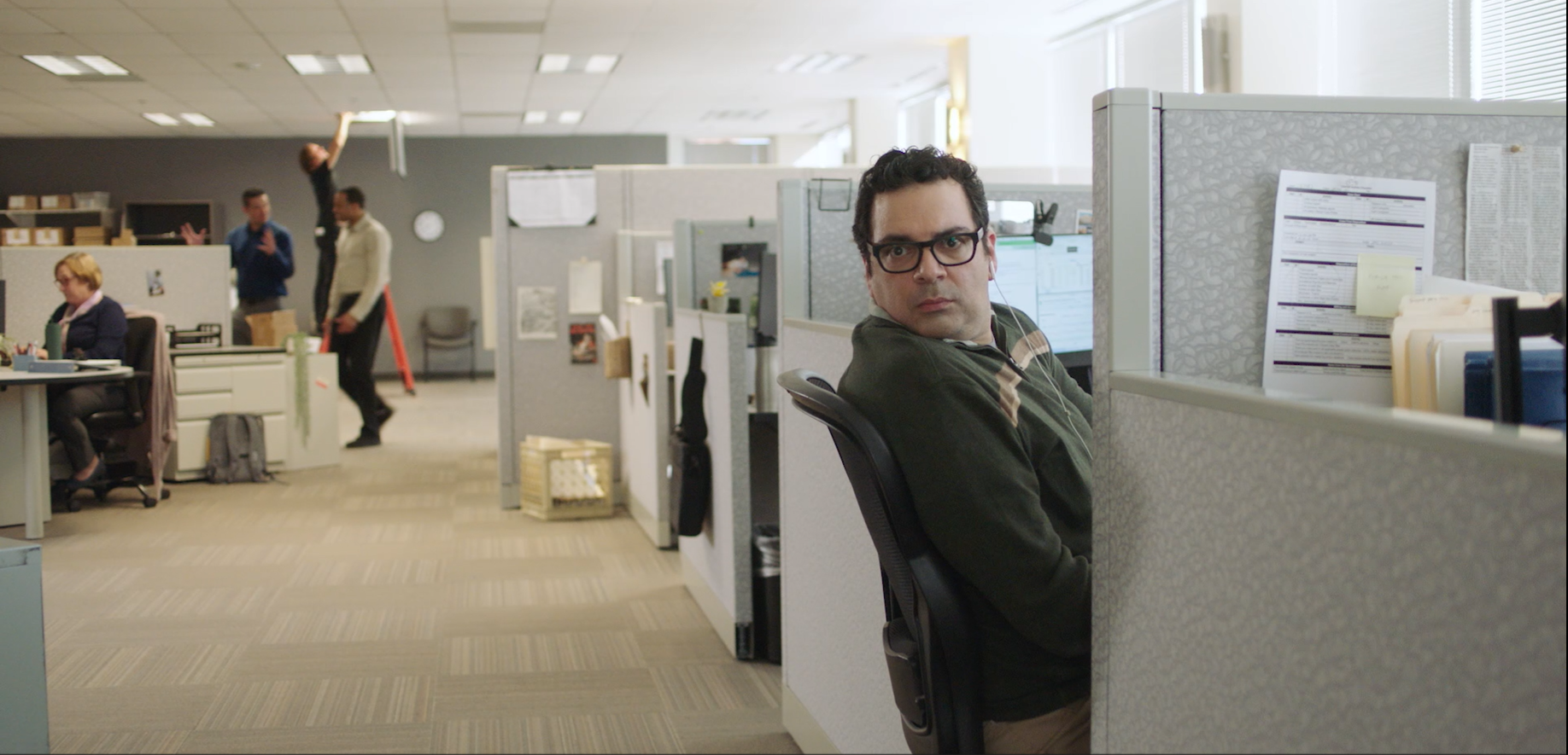 A man leaning out of his cubicle quizically