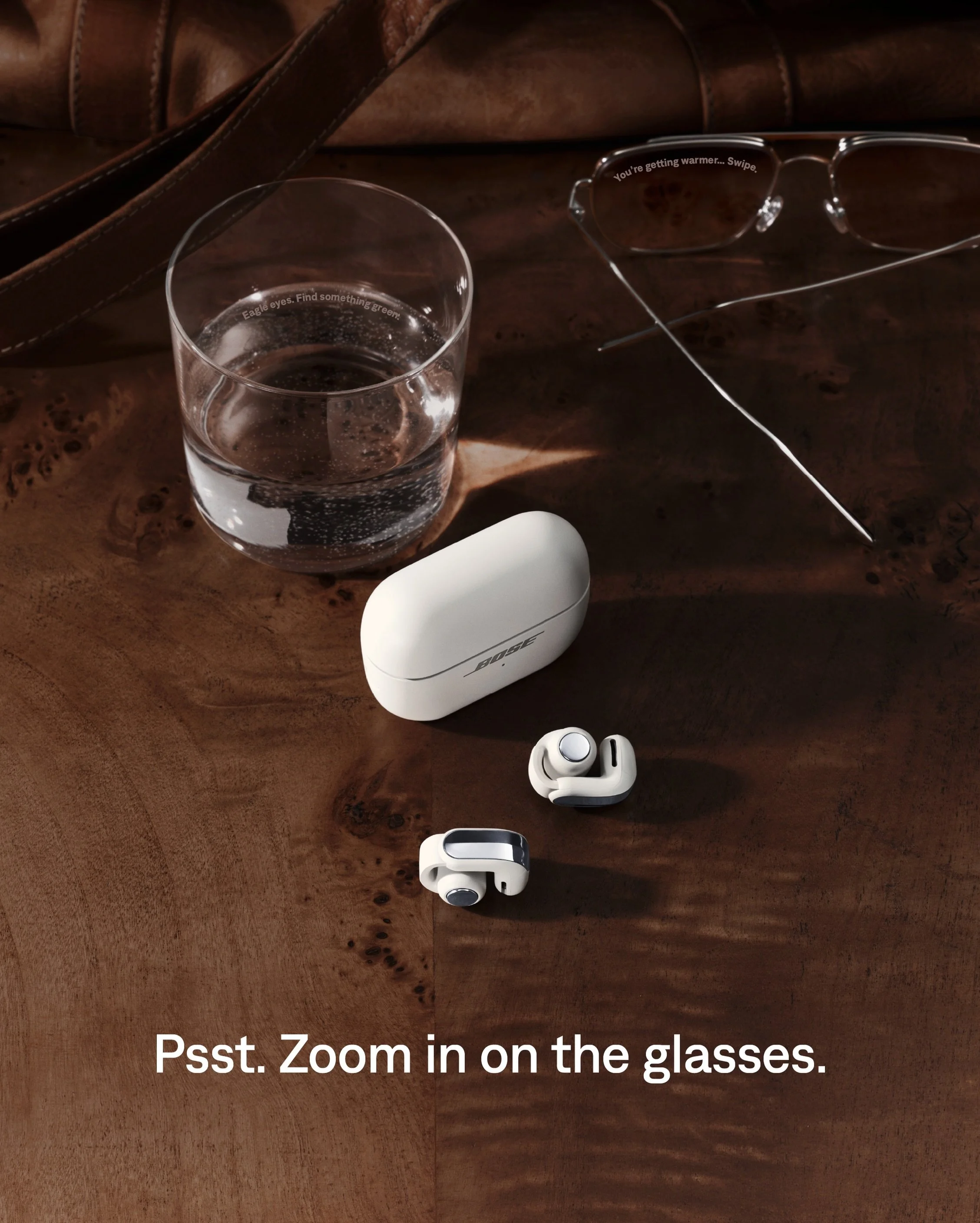 Bose 'open secret' teaser — leather bag, glass and sunglasses with hidden message text