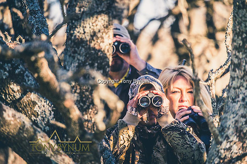 Hunters using their binoculars to spot game using a tree for cover. La Pampa, Argentina ©tonybynum.com