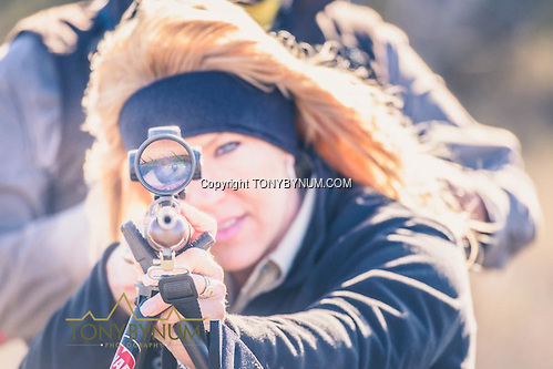 A woman looking though the scope on a hunting rifle. La Pampa, Argentina ©tonybynum.com