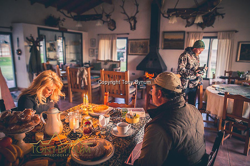 Power is sometimes an issue in La Pampa. Just in case it goes out, there are always candles on had. Candle lit breakfast offers a quanta, more romantic experience. Here a husband and wife sit at the breakfast table together. La Pampa, Argentina ©tonybynum.com