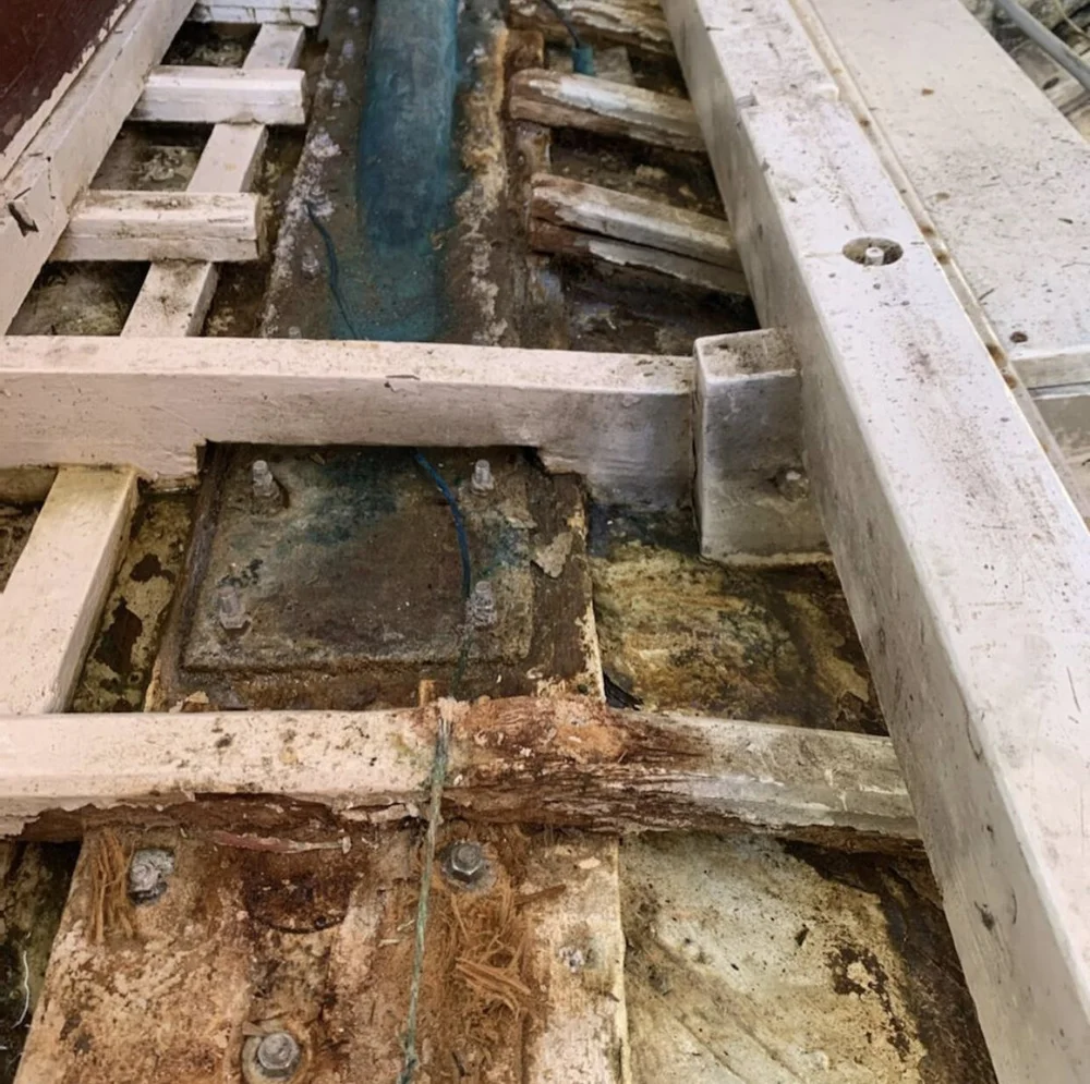 A hull under repair on hard standing inside the Fremantle Sailing Club shed