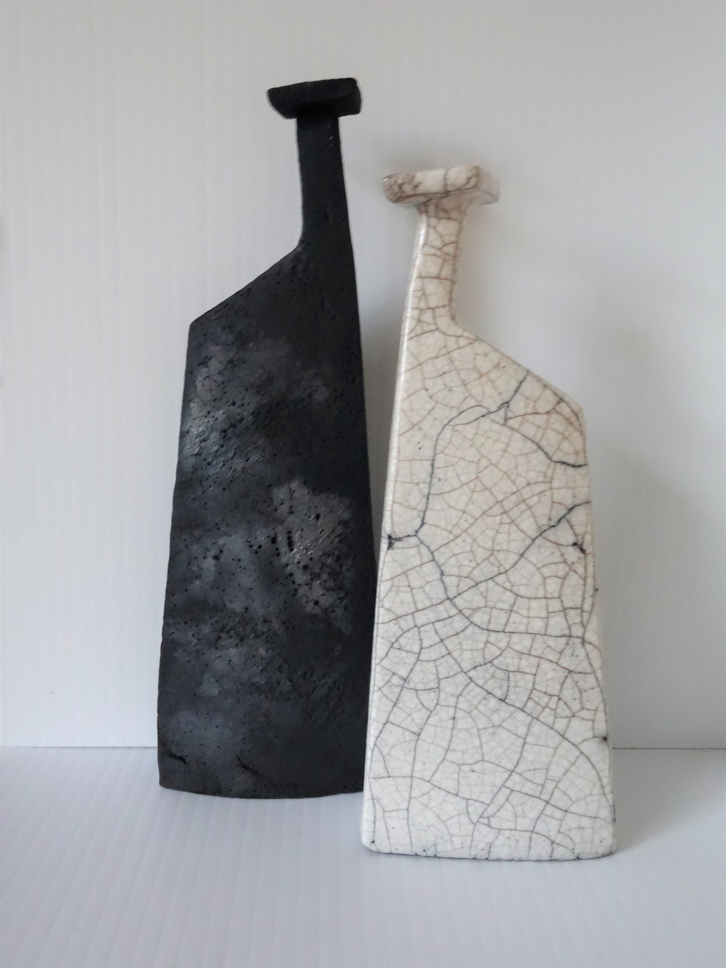  (LEFT)  Title: Matt Black Bottle (square top) Size: 19 cm (h) x 7 cm (w) Medium: Smoke Fired Price: £90  (RIGHT) Title: White Raku Bottle (square top) Size: 17 cm (h) x 7 cm (w) Medium: Raku  Price: £90 