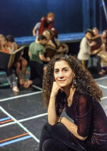 Kari Margolis, creator of Margolis Method kneels in front of the camera with groupings of her students in different physical positions behind her.