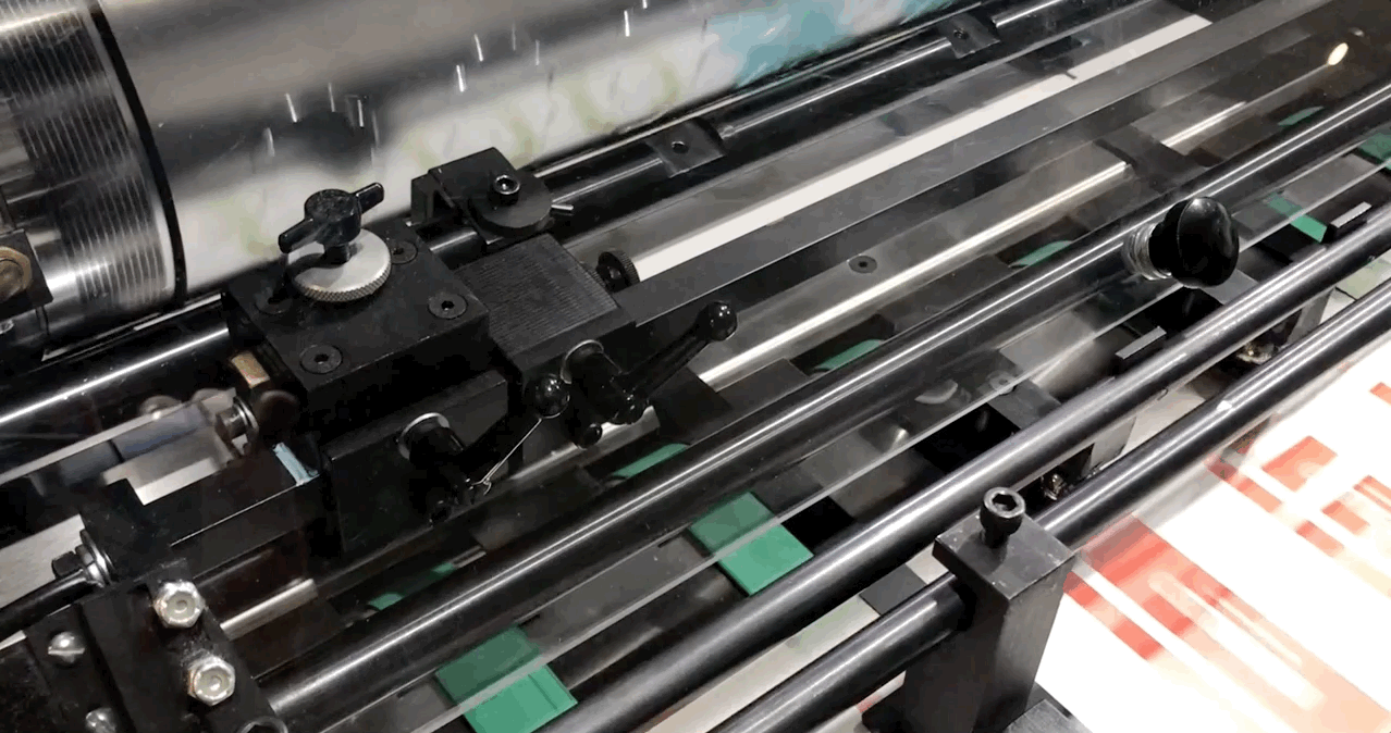 Left-hand pull register on Insignia machines. Head stops are stopping lead edge of sheet, side guide is pulling sheets to a register pin & gripper fingers are grabbing & pulling each sheet through the cutting cylinders. Insignia machines are capable of registering to both left and right hand sides of a sheet. 