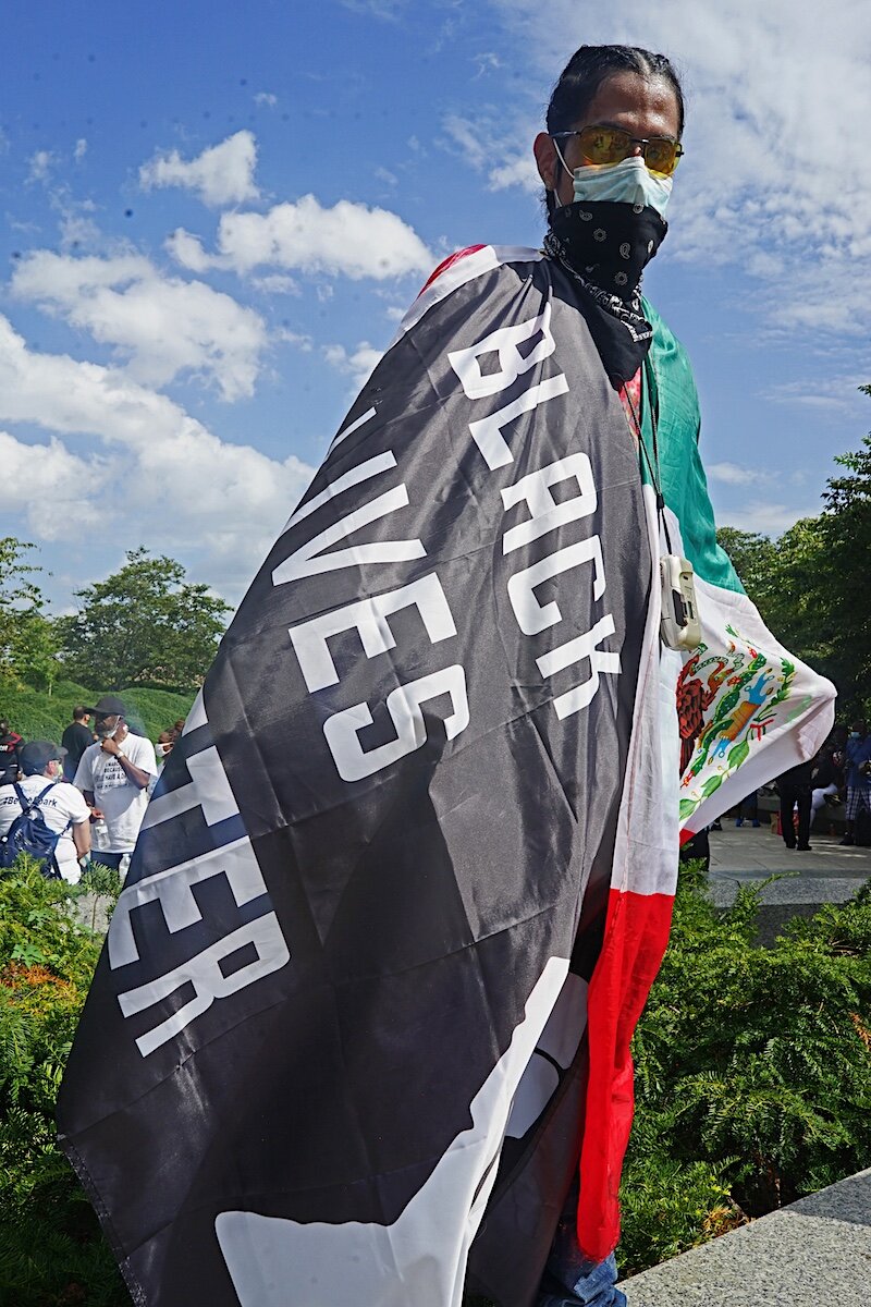  August, 2020 - Washington DC - Irv, from Queens, NY drove to D.C to participate in the march. He poses for a portrait with his native Mexican and a Black Lives Matter flag. ‘Police brutality must end.’” © Russell Frederick 