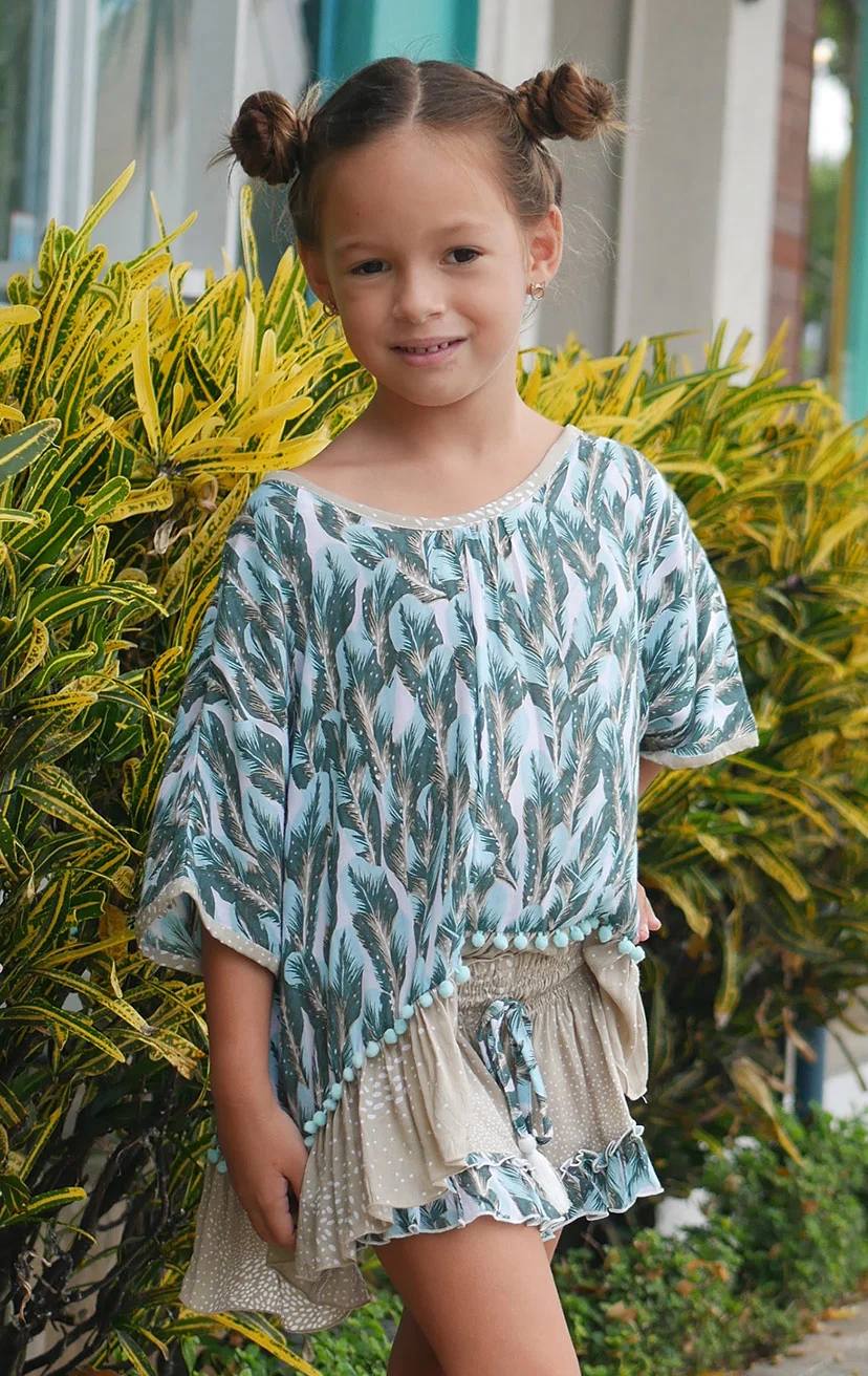 TOP ALLISHA Cap sleeve tunic top, bottom ruffle w/ pom pom detail 100% RAYON | 2/3 | 4/5 | 6/7 | 8/10 – SHORTS BLOOMIN Elastic waist shorts, drawstring w/ tassels, bottom ruffle detail 100% RAYON | 2/3 | 4/5 | 6/7 | 8/10