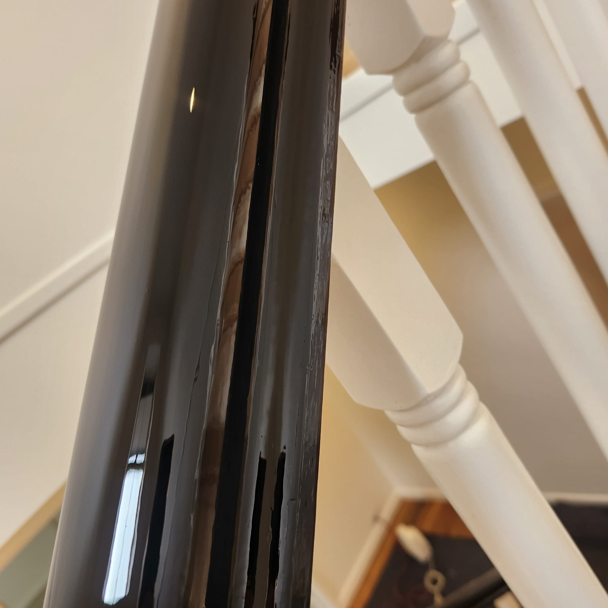 Close-up of the gap between a black metallic railing and a white wooden chair.