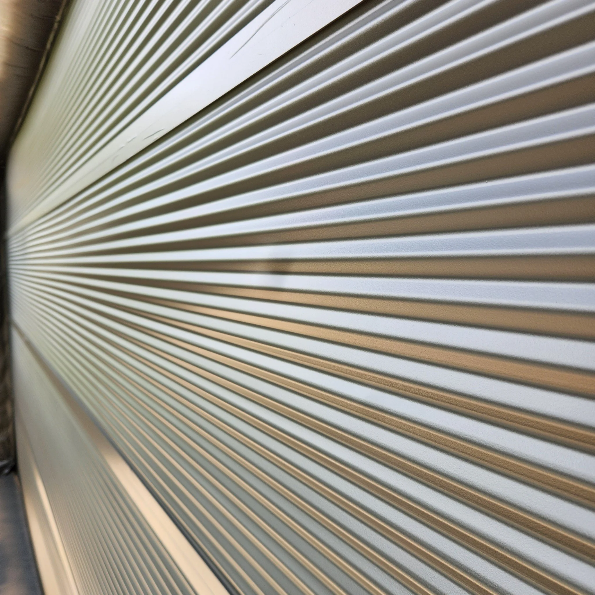 Close-up of a silver metallic rolling shutter door with horizontal ridges.