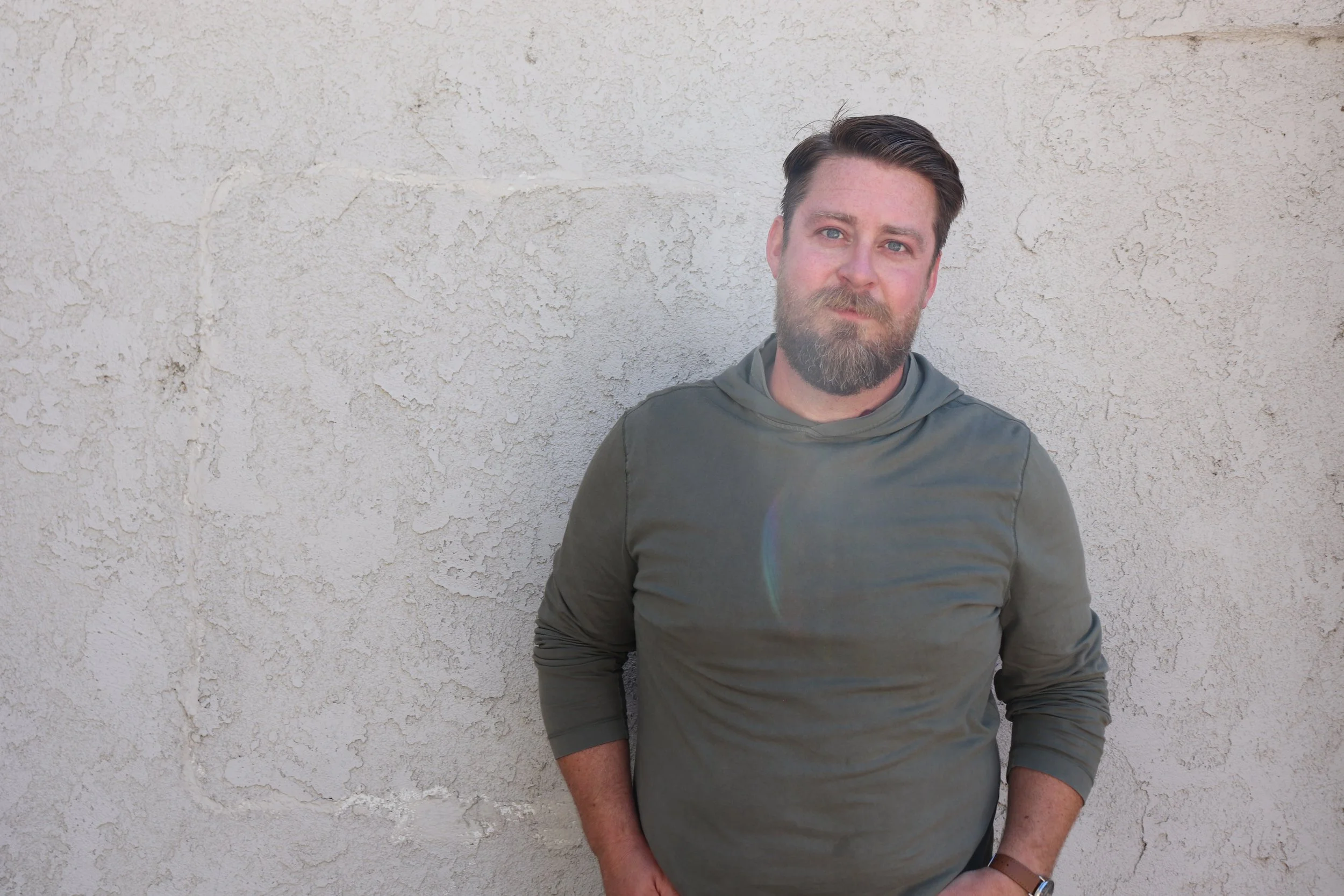 Portrait of Scott Treas in a green sweater against a white wall