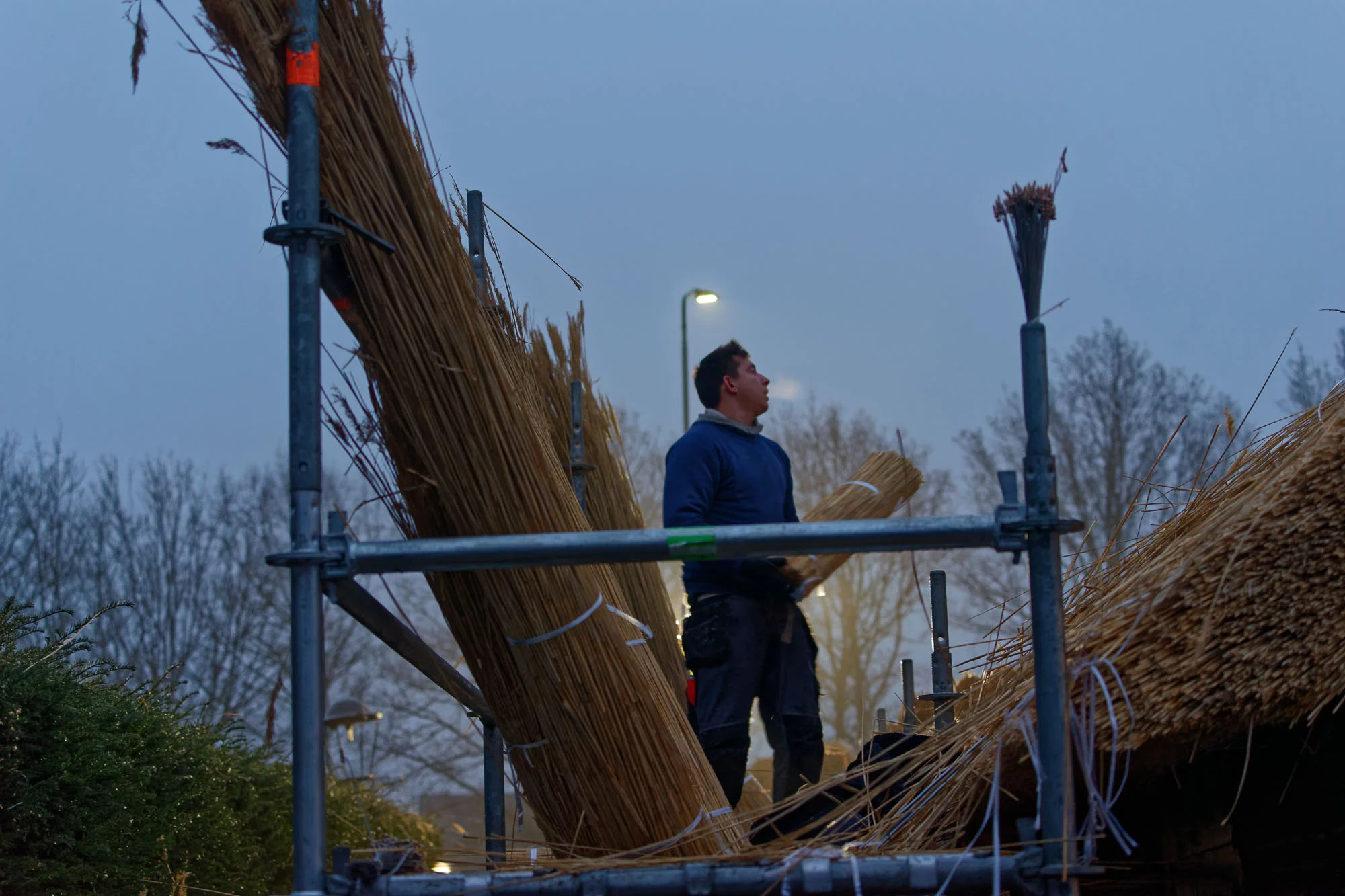 en werpt ze dan op naar de mannen die op het dak aan het werk zijn.