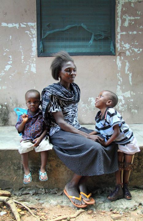 David looking up at his mother, Eunice before a Kekeli meeting. His younger brother sits next to them.