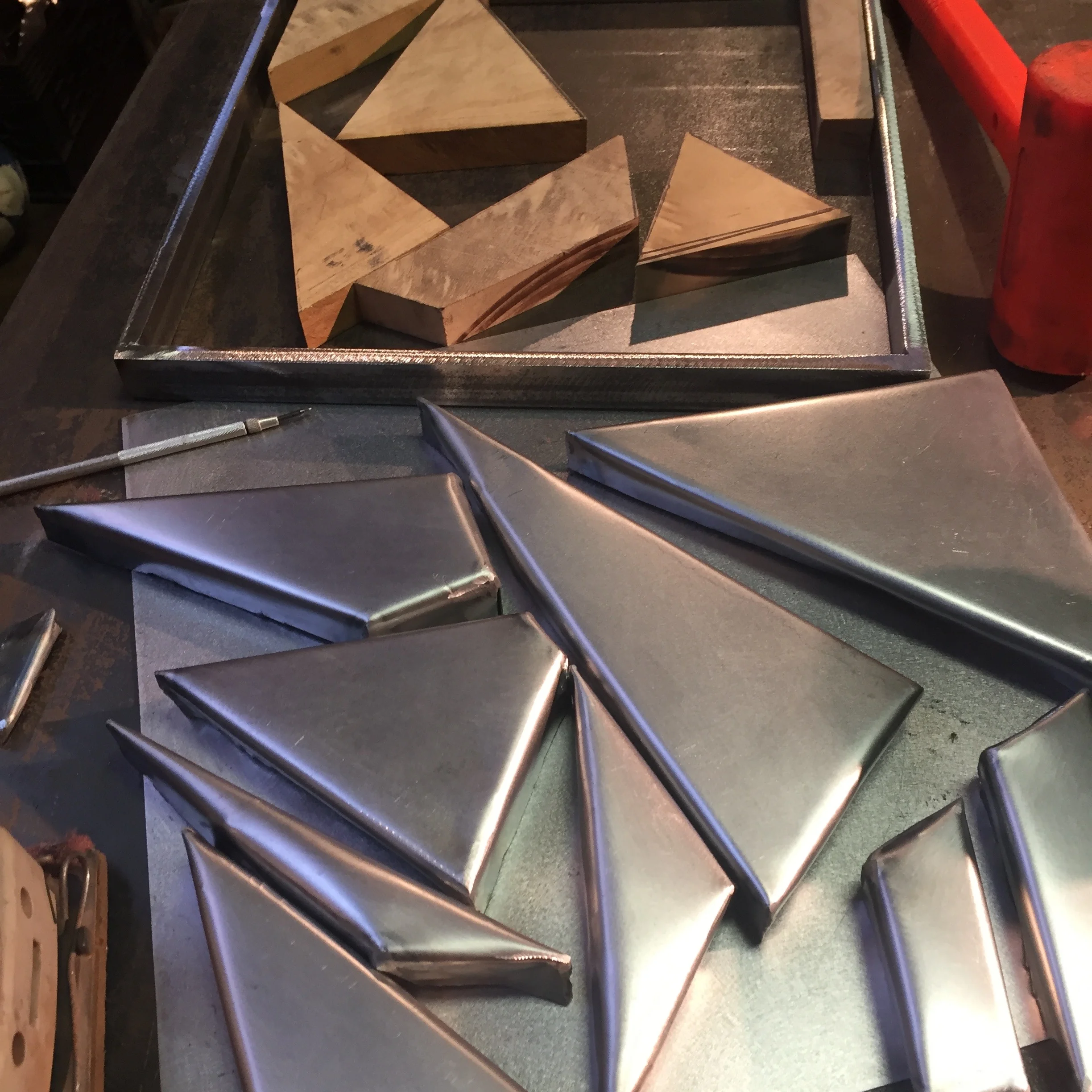 i then bend the metal to fit between the wood pieces. we cut a flat sheet of metal and bend each side with jigs and hammer. 