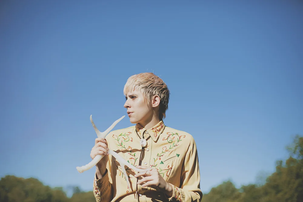 Izzy True clutching a rubbery antler and sporting Mommy's finest cowboy shirt. Photograph (c) Amanda Carbaugh