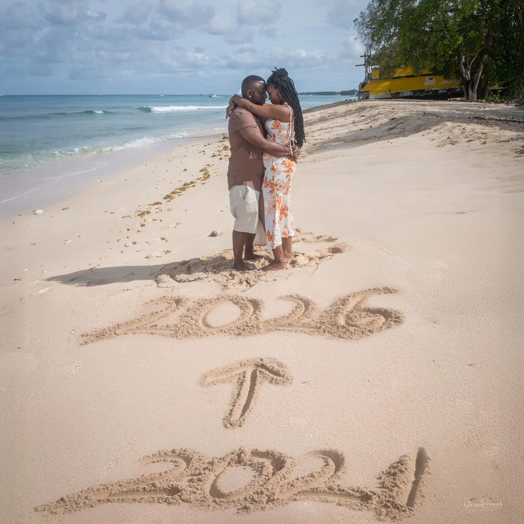 Couple embracing on the beach with the year 2022 written in the sand and an arrow pointing upward in the foreground.