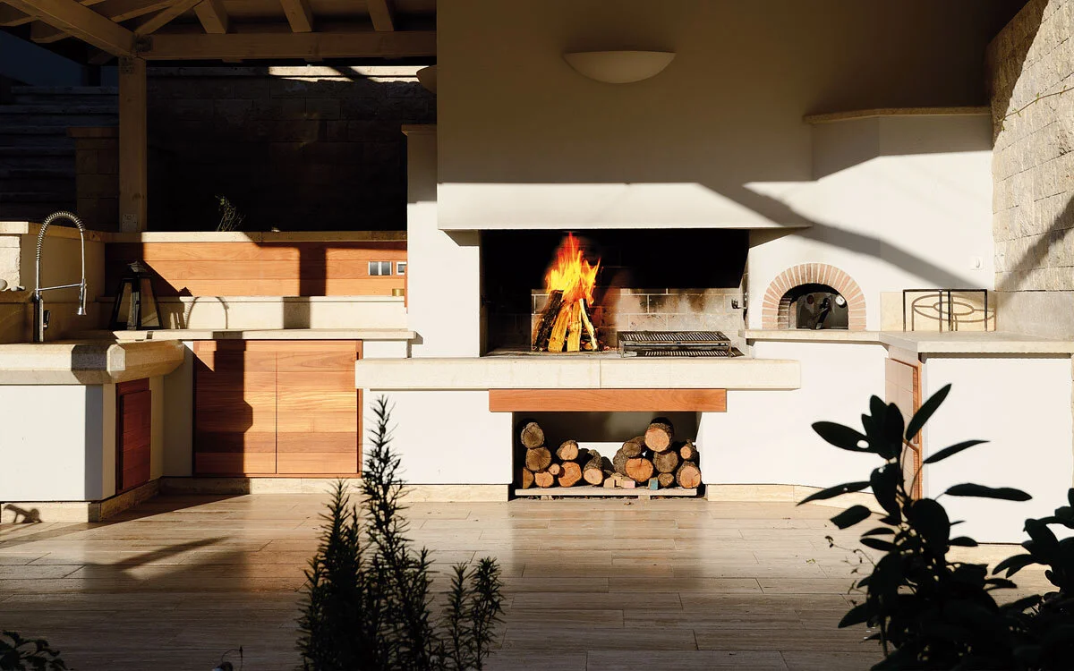 cucina-su-misura-da-esterno-composizione-con-lavello-e-piani-in-pietra,-camino-da-cottura-con-portalegna,-forno-a-legna-bis-gover-srl.jpg