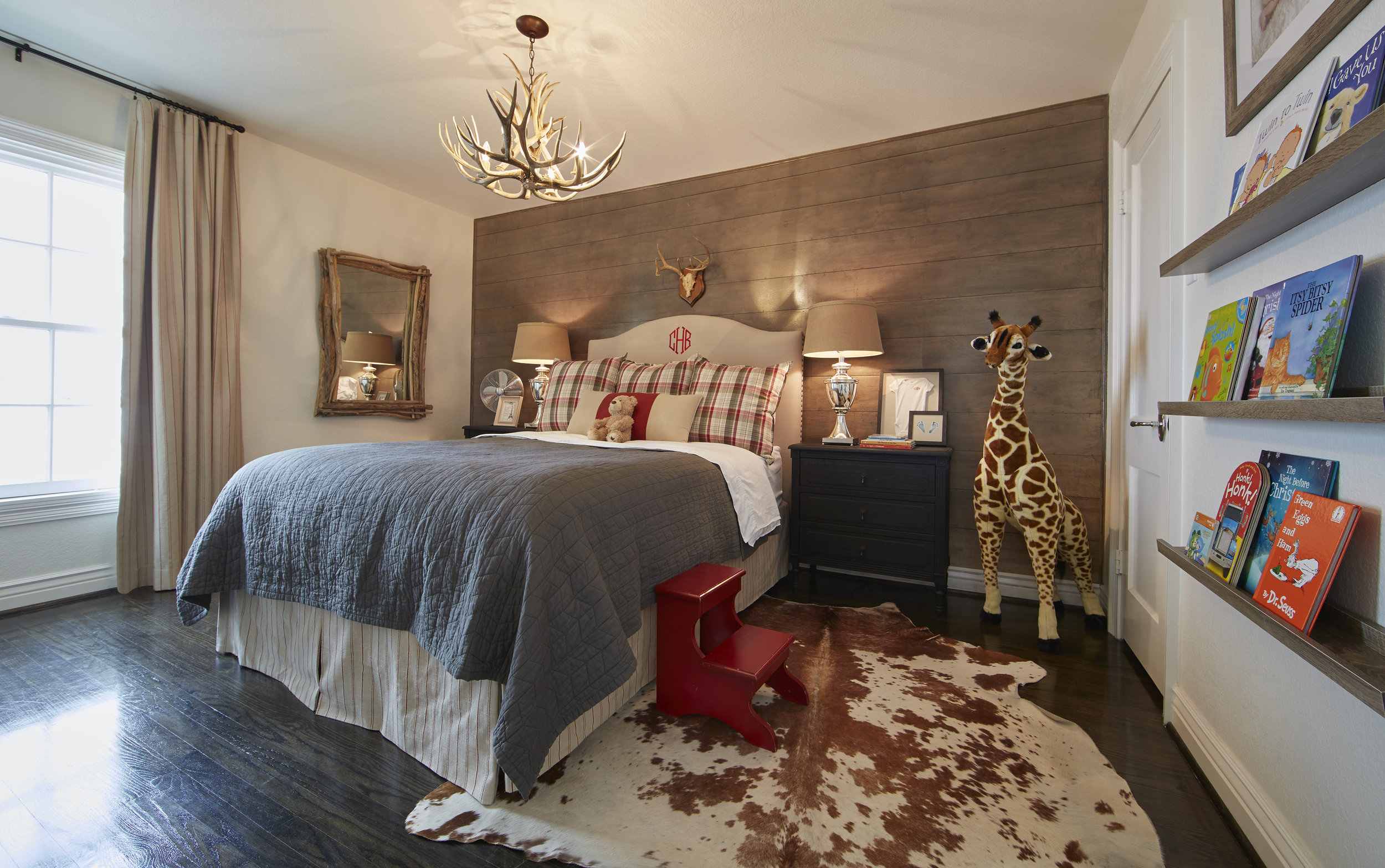 Son Beckham’s room features a more rustic take on farmhouse styling with its stained shiplap wall, antler chandelier and cowhide rug. Emily chose red accents to reflect his fiery personality.
