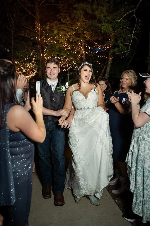 Bride and groom celebrating with friends at night under string lights, outdoors.