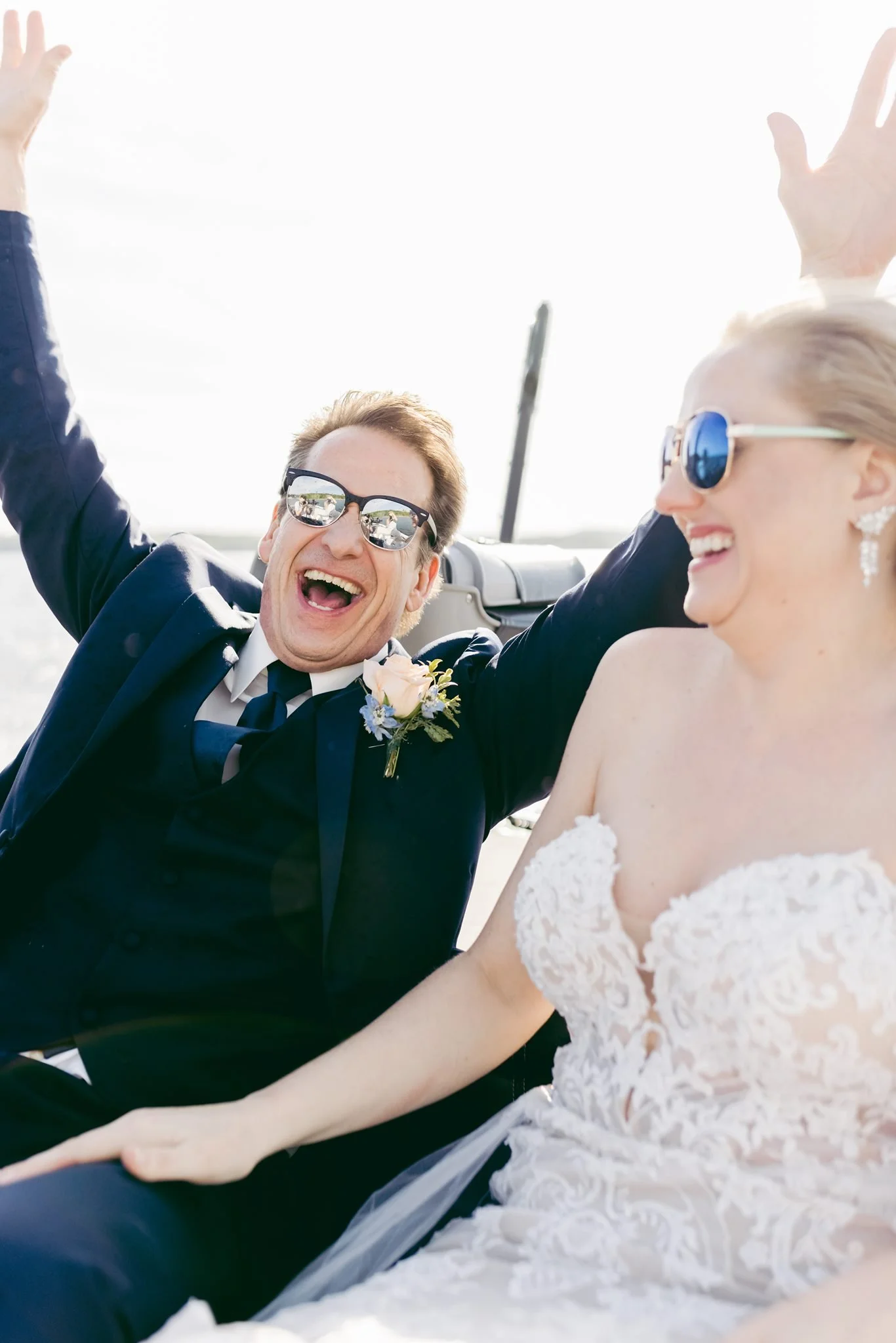 Happy bride and groom celebrating outdoors, both wearing sunglasses and smiling.