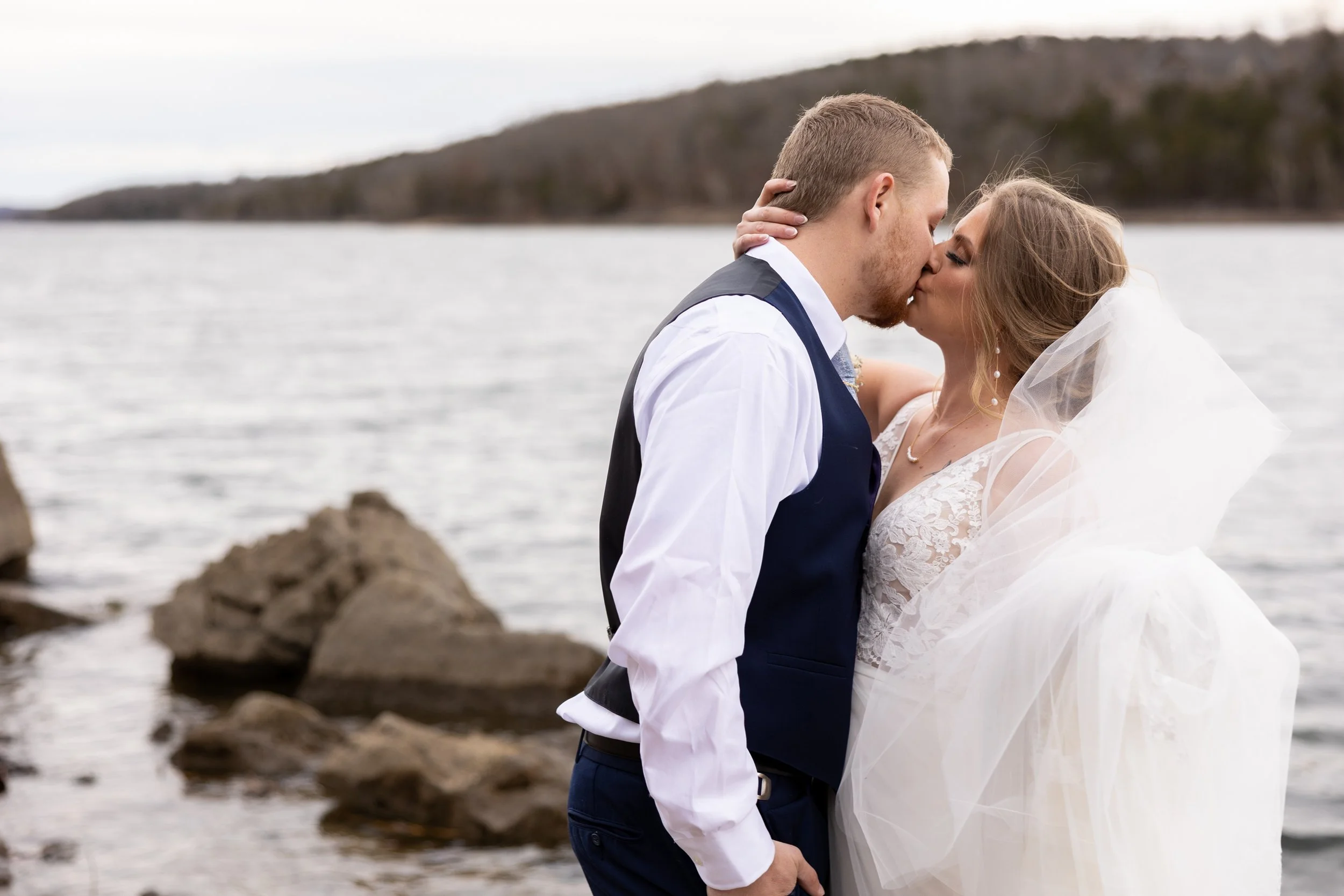 A bride and groom sharing a kiss on the beach during their wedding.