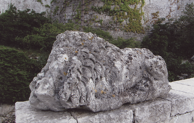Photograph of a stone lion whose features have been erased by the elements, transforming the sculpture into a lump of stone