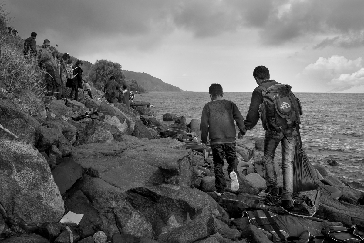 Hussein Nabizadeh, 32, holds his sons hand and he walks with other refugees, primarily from Syria, Iraq and Afghanistan who are being aided by volunteers as they disembark boats near Mithimna, on the island of Lesvos, Greece on September 28, 2015.