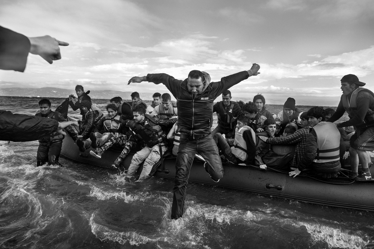 Refugees primarily from Syria, Iraq and Afghanistan are helped by volunteers as they disembark boats near Scala, on the island of Lesvos, Greece on September 30, 2015. The Agean sea is particularly rough, with the first signs of winter storms beginning today. Many refugees were sea sick, some to the point of life threatening conditions due to dehydration and cold.