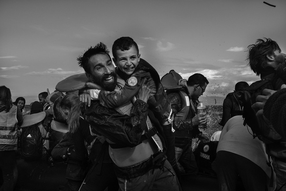  Kadoni Kinan, 26, a volunteer, helps a young Syrian boy as he disembarks a boat near Scala, on the island of Lesvos, Greece on September 30, 2015. Kadoni Kinan left his home in Saragep, Syria five years ago. Kinan successfully filed for refugee stat