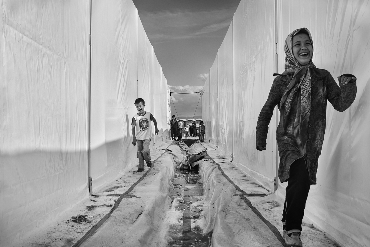 Two children play while they wait at a refugee transit camp, or reception center for refugees and migrants, in Idomeni, Greece on October 2, 2015. Idomeni camp has between 5,000 and 10,000 people pass through a day, and as the crisis continues, the conditions at the camp get slightly better. From here, refugees walk into Macedonia, and then board a special train to the Serbian border.