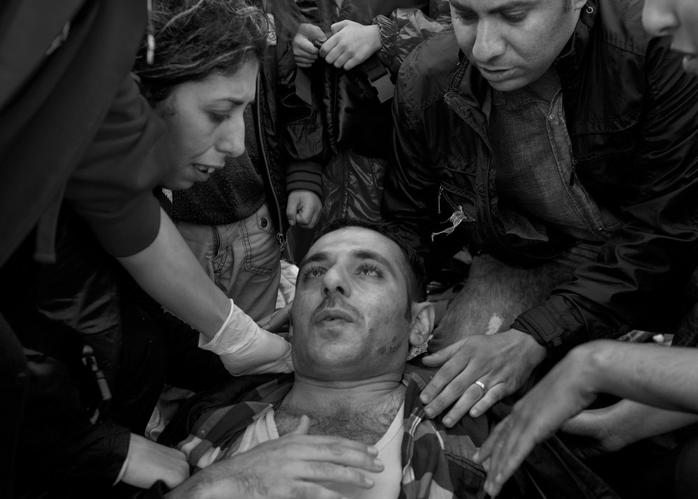  Family and volunteers surround a refugee who collapsed on a beach after arriving in an overcrowded dinghy on the Greek island of Lesbos from Turkey on September 24, 2015. 