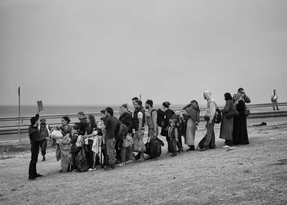 Refugees wait in a queue for a bus organized by the local NGOs to go toward registration camp near Mytilene on September 23, 2015. 