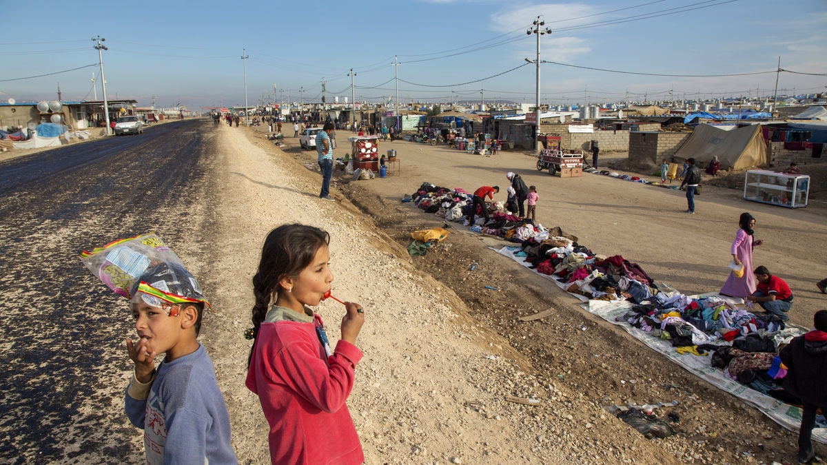  A young girl enjoys a lollipop while watching shoppers in the Domiz Camp for Syrian Refugees just outside of Dohuk, Iraq on Nov. 23, 2013. 