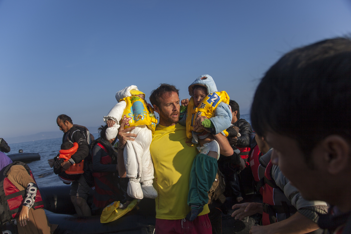 A Spanish volunteer lifeguard helps refugees arrive on the Greek island of Lesbos.